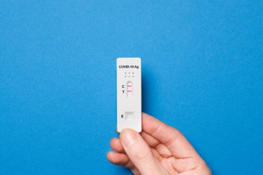 Mavi arka planda karbondioksit 19 için hızlı test cihazı kullanarak elde pozitif sonuç elde tutuyoruz. Evde Corona virüsü enfeksiyonu teşhisi