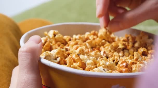 Close up widok na kobiecej dłoni trzymając popcorn podczas oglądania filmu w salonie — Wideo stockowe