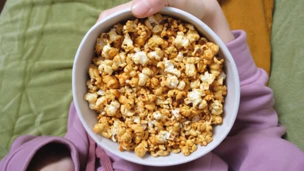 Close up widok na kobiecej dłoni trzymając popcorn podczas oglądania filmu w salonie — Wideo stockowe