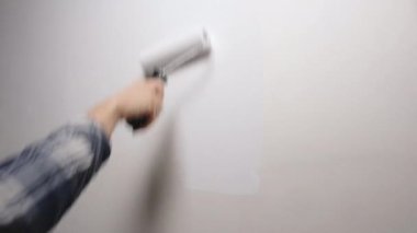 Roller 'ın beyaz boyayla boyadığı duvar. Beyaz boyalı bir boya silgisiyle çıplak bir duvar boyamak. 4K çözünürlük videosu