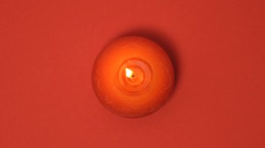 Kırmızı arka planda izole edilmiş kırmızı yanan mum. 4k çözünürlüklü yanan mumlu video pankartı.