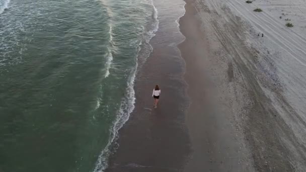 美しい素足の女性捨てられたビーチに沿って歩く。海のビーチ、海岸線、ウォーキングガールでドローンの空中ビュー。4K解像度ビデオ. — ストック動画
