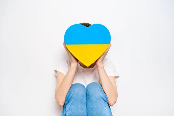 Frau mit einer großen gelben und blauen Schachtel in Herzform. Trendiges Banner in der Farbe der ukrainischen Flagge — Stockfoto