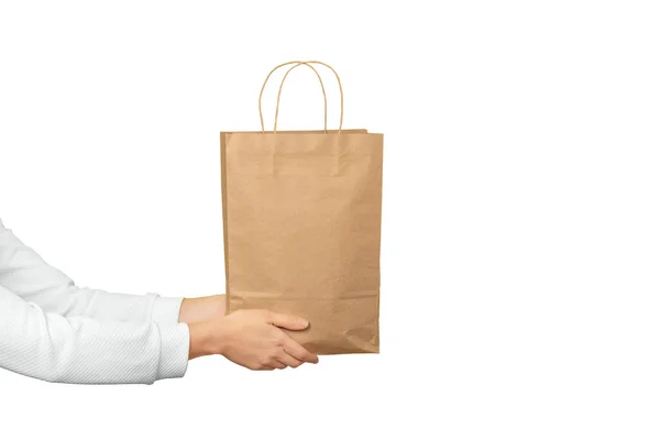 Женские руки держат большой подарочный пакет из коричневой бумаги ремесла на белом фоне. Концепция подарков, подарков или электронных покупок. — стоковое фото