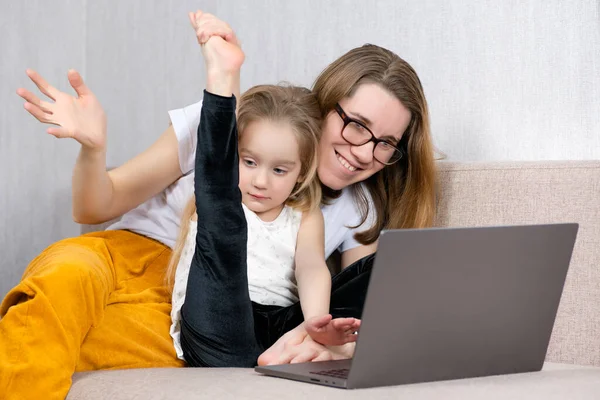 La bambina dimostra alla sua famiglia su un computer portatile le sue abilità nella danza e nella ginnastica. comunicazione online con i parenti — Foto Stock