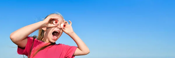 Surpreendida adolescente em uma camiseta rosa olha para os binóculos gigantes de olhos gelatinosos à frente. Banner com espaço de cópia. — Fotografia de Stock