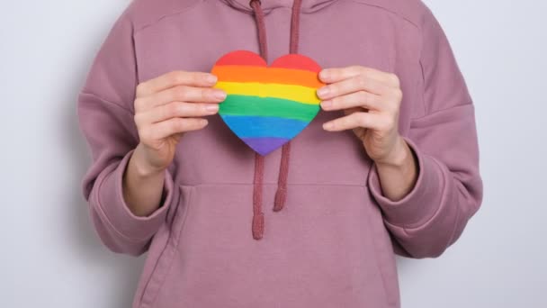 Woman or girl in purple hoodie holding heat painted in colors of Gay Pride Flag Colorful symbol of LGBTQIA 4K resolution video banner. — Stock Video