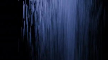 Mavi parlayan parçacıkların arka plandaki yavaş çekim videosu. Parlayan ışık parçacıkları düşer. Super 4k çözünürlüklü videoda Düşen Parıltı Arkaplanı