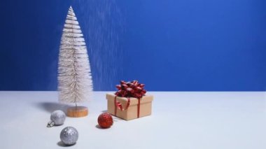 Fotokopi alanı olan güzel bir Noel ya da yeni yıl afişi. Oyuncak Noel ağacı, kırmızı fiyonklu hediye kutusu ve mavi arka planda Noel mücevherleri. Arka planda kar yağıyor..