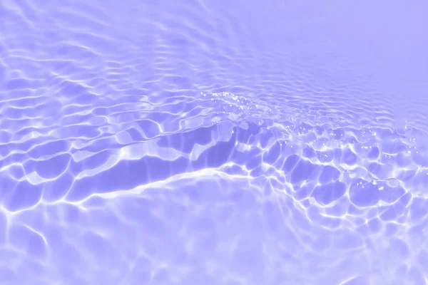 Pure swimming pool water background toned in purple color with sun ray lights on it. Sun reflections on water waves. Trendy summer banner with copy space.