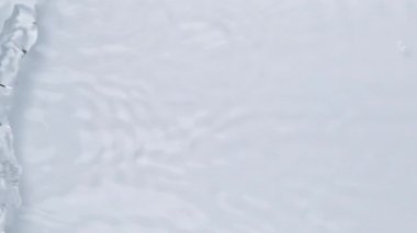 Su dokusuna yakın görünüm ve su üzerindeki dalgalar video modellemesi için etki yaratıyor. Işığın dalga kırılma etkisiyle organik açık gri gölge etkisi. Yavaş çekim tam HD video pankartı.