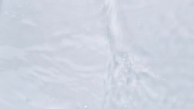 Su dokusuna yakın görünüm ve su üzerindeki dalgalar video modellemesi için etki yaratıyor. Işığın dalga kırılma etkisiyle organik açık gri gölge etkisi. Yavaş çekim tam HD video pankartı.