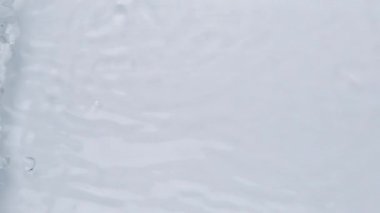 Su dokusuna yakın görünüm ve su üzerindeki dalgalar video modellemesi için etki yaratıyor. Işığın dalga kırılma etkisiyle organik açık gri gölge etkisi. Yavaş çekim tam HD video pankartı.