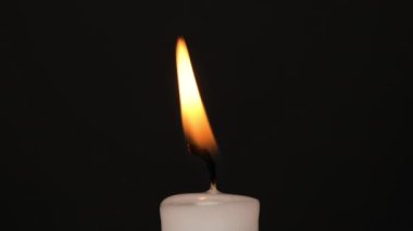 White single Candle flickering in the dark. Side view. White candle burning on the dark background. Slow motion full HD video