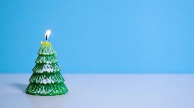 Mavi arkaplanda yanan yeşil Noel ağacı mumu ya da fotokopi alanı olan Noel videosu afişi