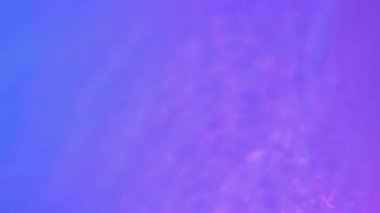 Neon Blue, pink and purple Water gradient texture with drops, splashes and waves. Organic water toned in blue and pink gradient with the refraction of light slow motion video banner.