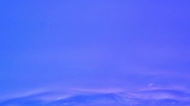 Neon Blue, pink and purple Water gradient texture with drops, splashes and waves. Organic water toned in blue and pink gradient with the refraction of light slow motion video banner.