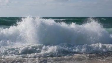 Atlantik Okyanusu 'nun boş sahillerinde köpükle ve su sıçramalarıyla yüksek dalgaların görüntüsünü kapat. Yavaş çekim Boş güzel okyanus kumsalının HD videosu.