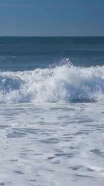 Atlantik Okyanusu 'nun boş sahillerindeki yüksek dalgaların güzel dikey görüntüsü. Terk edilmiş güzel bir okyanus plajı. Tam HD yavaş çekim deniz video pankartı.