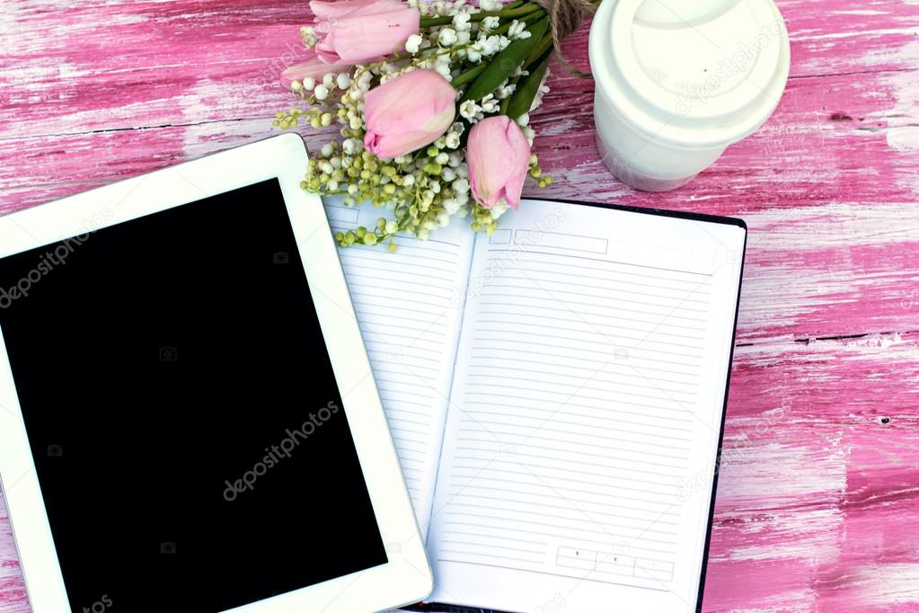 diary, a tablet computer, a glass of coffee and  lilies of valle