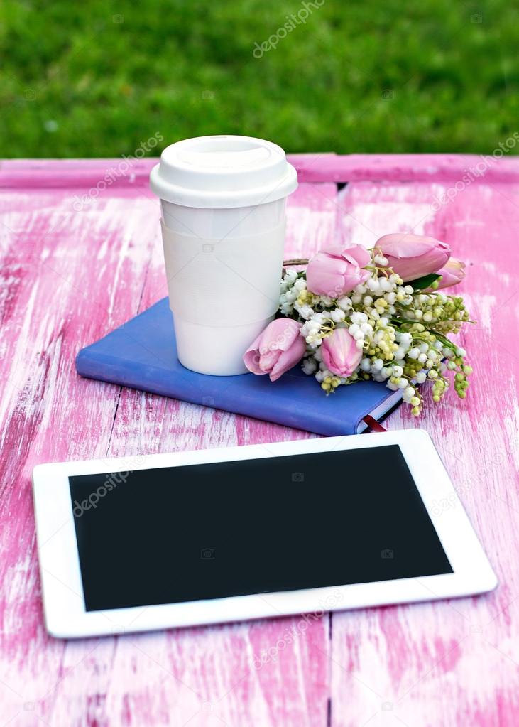 diary, a tablet computer, a glass of coffee and  lilies of valle