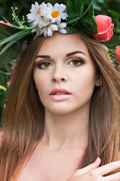 Mooie jonge vrouw met een krans van bloemen op haar hoofd — Stockfoto