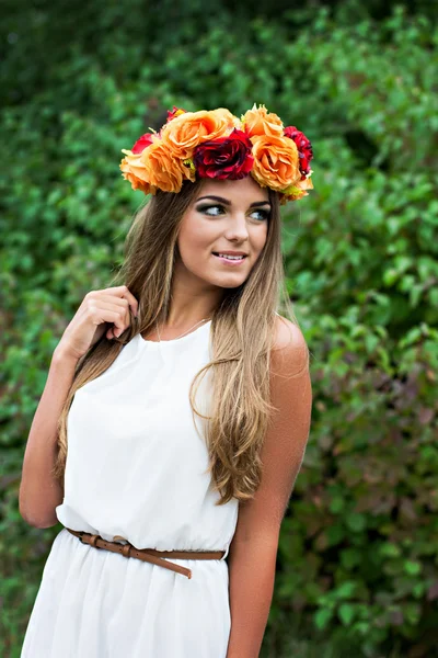 Mooie jonge vrouw met een krans van bloemen op haar hoofd — Stockfoto