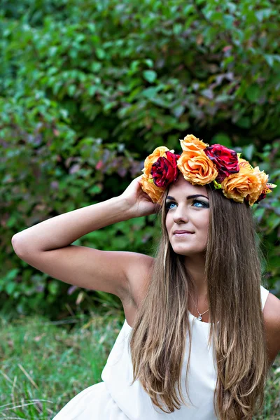 Όμορφη νεαρή γυναίκα με ένα στεφάνι από λουλούδια στο κεφάλι της — Φωτογραφία Αρχείου