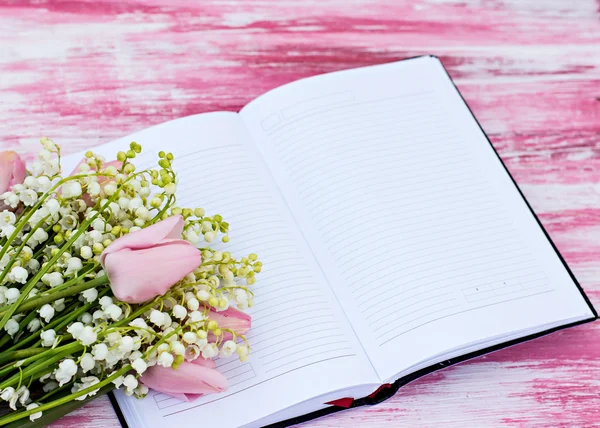 Notebook and a bouquet of lilies of valley and tulips — Stock Photo, Image