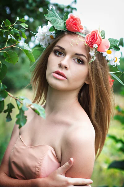 Belle jeune femme avec une couronne de fleurs sur la tête — Photo