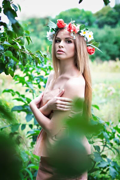 Mooie jonge vrouw met een krans van bloemen op haar hoofd — Stockfoto