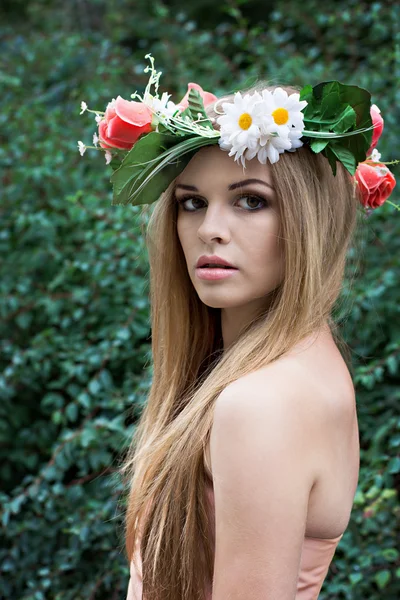 Mooie jonge vrouw met een krans van bloemen op haar hoofd — Stockfoto