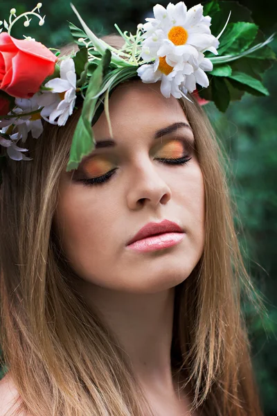 Mooie jonge vrouw met een krans van bloemen op haar hoofd — Stockfoto