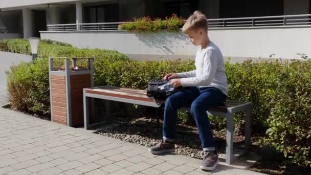 Blond pojke tar en plastflaska vatten från skolan ryggsäck och drycker — Stockvideo