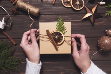 Kadınların elleri Noel hediye kutusunu çevre dostu doğal süslemelerle süsler..