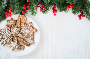 Noel ev yapımı zencefilli kurabiye ve beyaz ahşap arka planda köknar dalları.