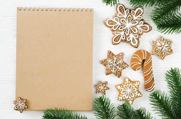 Christmas gingerbread and brown notebook on white wooden table. — Stock Photo, Image