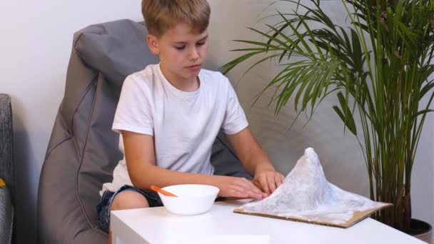 Schoolboy faz projeto criativo em forma de papel mache montanha. — Vídeo de Stock