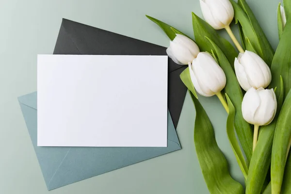 Préparation d'une carte de vœux. Carte blanche vierge avec enveloppe vert pâle, modèle maquette. — Photo