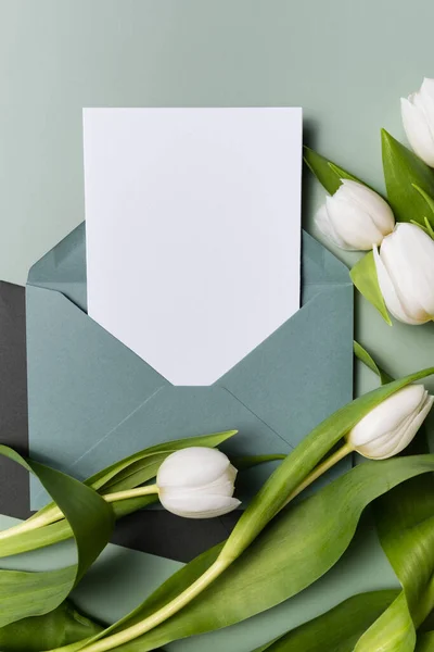Макет паперової ковдри конверт запрошення або вітальна листівка і білі тюльпани . — стокове фото