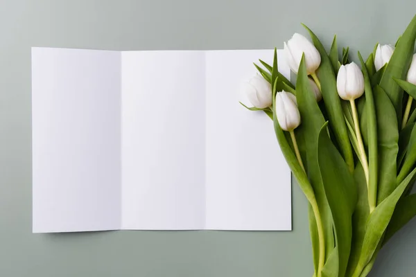 Fehér mockup trifold brosúra halványzöld háttér egy csokor fehér gyönyörű tulipán. — Stock Fotó