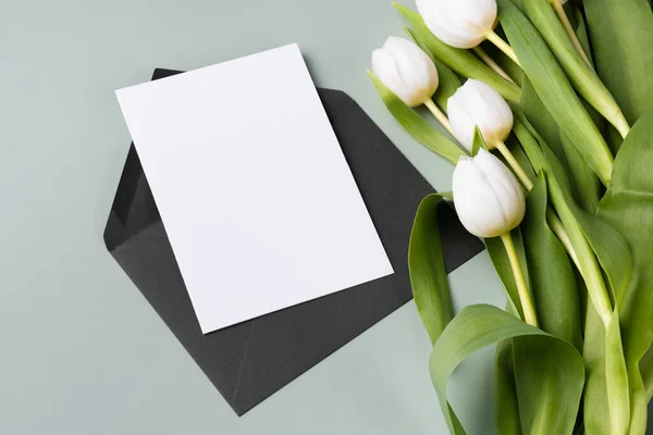 Tarjeta de invitación o de felicitación en blanco de papel burlón y ramo de tulipanes blancos. —  Fotos de Stock