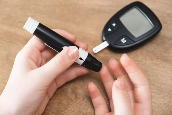 Ręce dziecka za pomocą Lancet na palcu, aby sprawdzić poziom cukru we krwi przez glukometer. — Zdjęcie stockowe