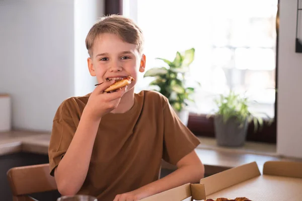 Szczęśliwy nastolatek cieszy się jedząc pyszną pizzę w domu. Świeżo upieczona pizza pepperoni — Zdjęcie stockowe