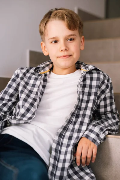 Elegante ragazzo adolescente sorridente mentre posa per una bella foto mentre seduto sui gradini. — Foto Stock