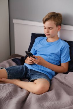 Zoomer evde yatağında yatarken telefonunu kullanıyor. Bir gencin sosyal hayatı, mobil iletişim..