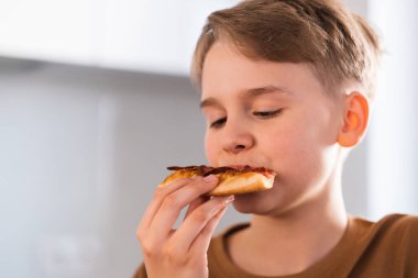 Memnuniyetle evdeki mutfakta lezzetli bir pizza yiyen adam. Yemek servisi. Fast food