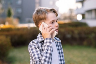 Şehirde telefonla konuşan genç bir adamın portresi. Modern gençlik, gençlerin yaşam tarzı