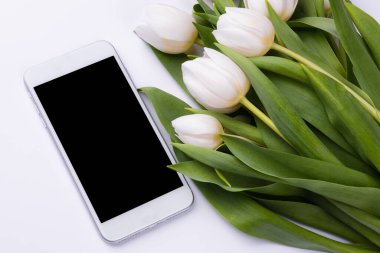 Bir buket beyaz laleli akıllı telefon modeli. Aygıt ekranı sunum veya uygulama tasarımı için şık arkaplan üzerinde maket yapın