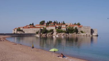 Karadağ 'ın güneşli yaz gününde Sveti Stefan adası yakınlarındaki güzel boş plaj Adriyatik Denizi, Budva, Karadağ, 4K' da butik oteli bulunan Sveti Stefan lüks turistik tatil beldesi
